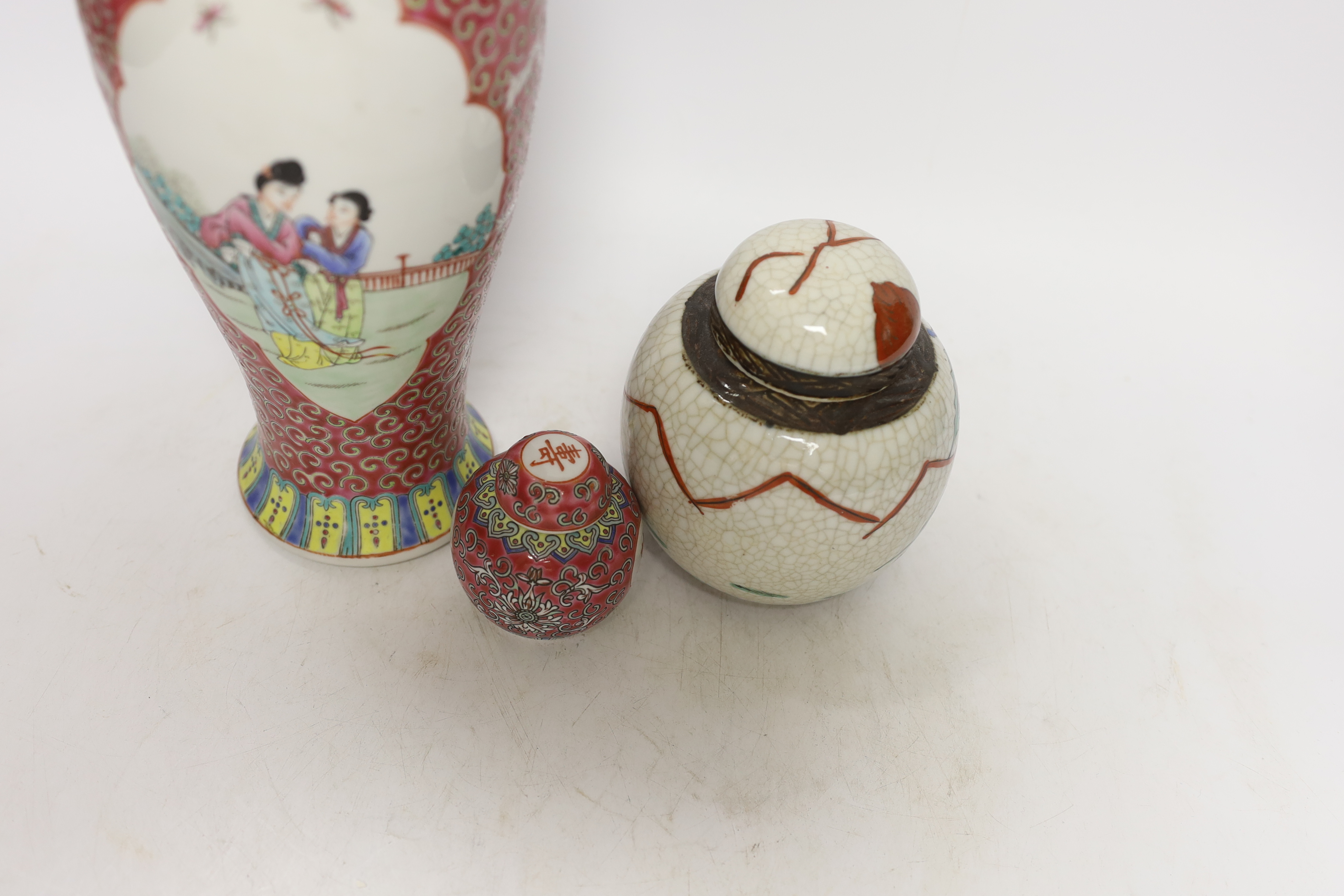 An early 20th century Chinese famille rose vase and cover, similar small jar and cover and a famille verte crackleglaze jar and cover, tallest 31cm